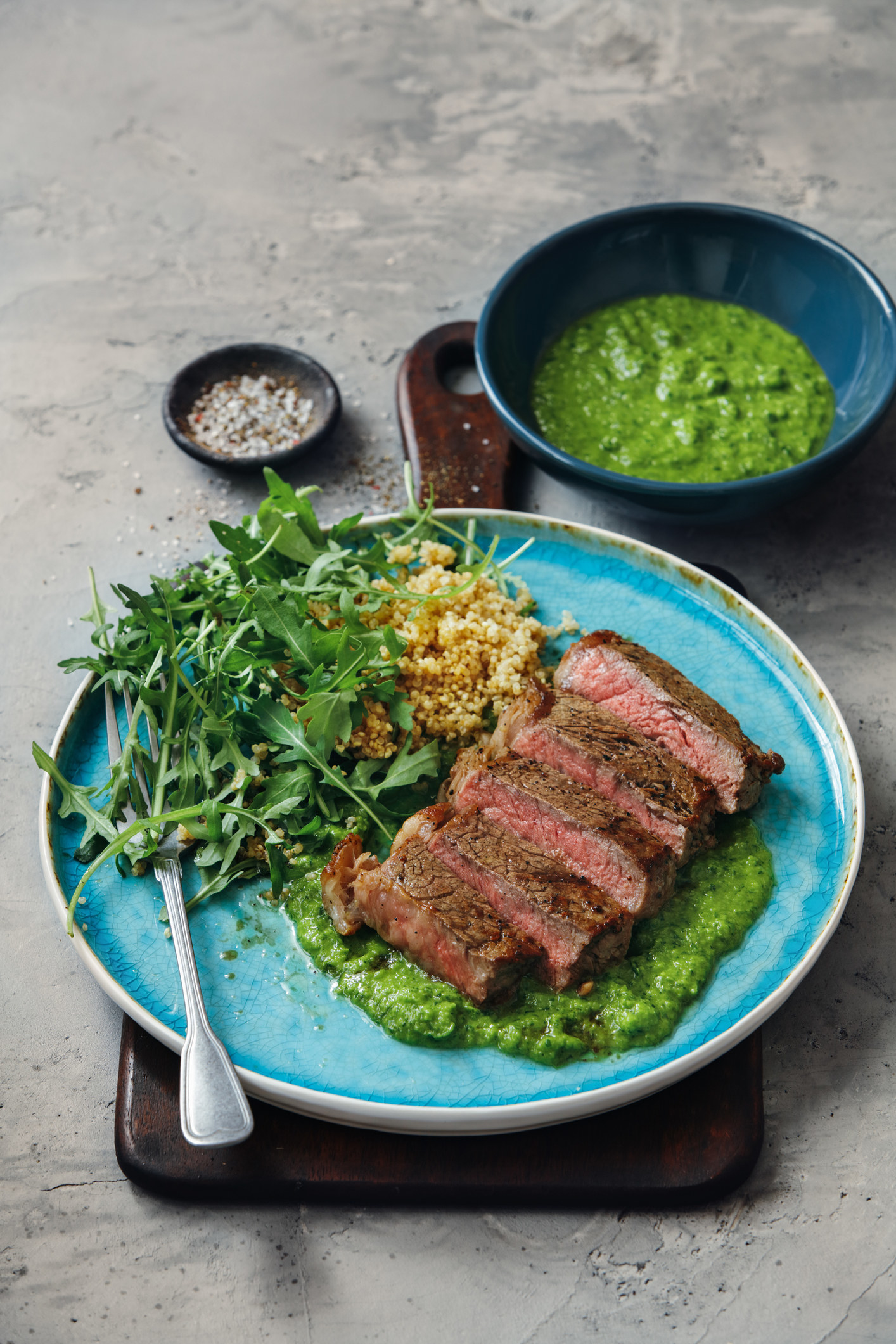 Sliced steak with couscous, arugula, and chimichurri.