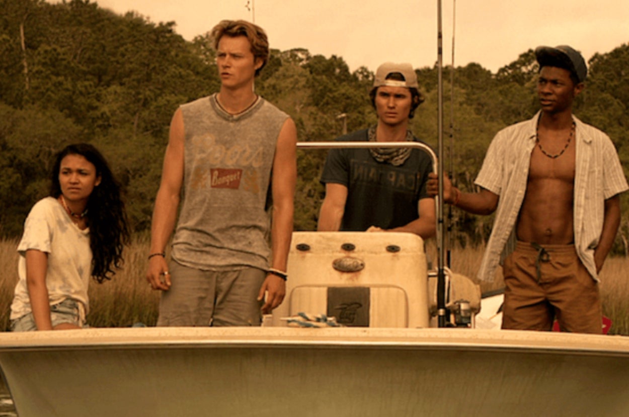 Kiara, JJ, John B, and Pope stand on a small boat as it goes through a swamp