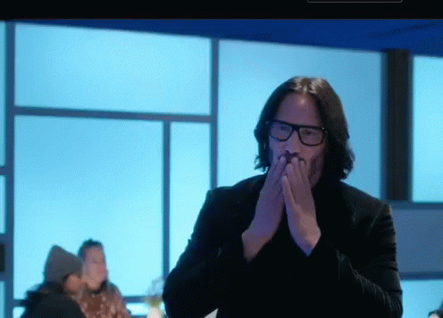 Keanu Reeves uses both his hands to blow kisses in slow motion