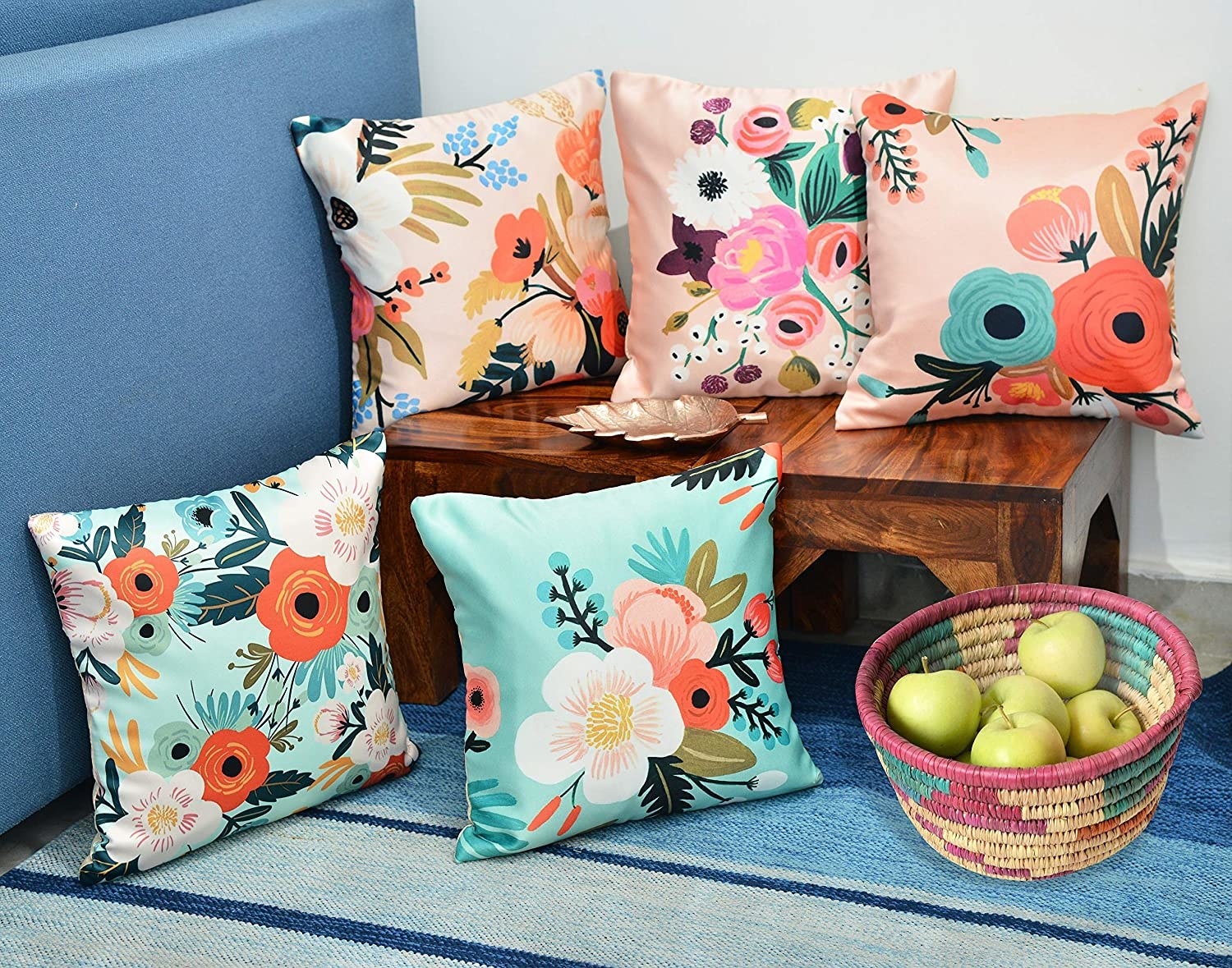 Floral cushions on a sofa next to some apples