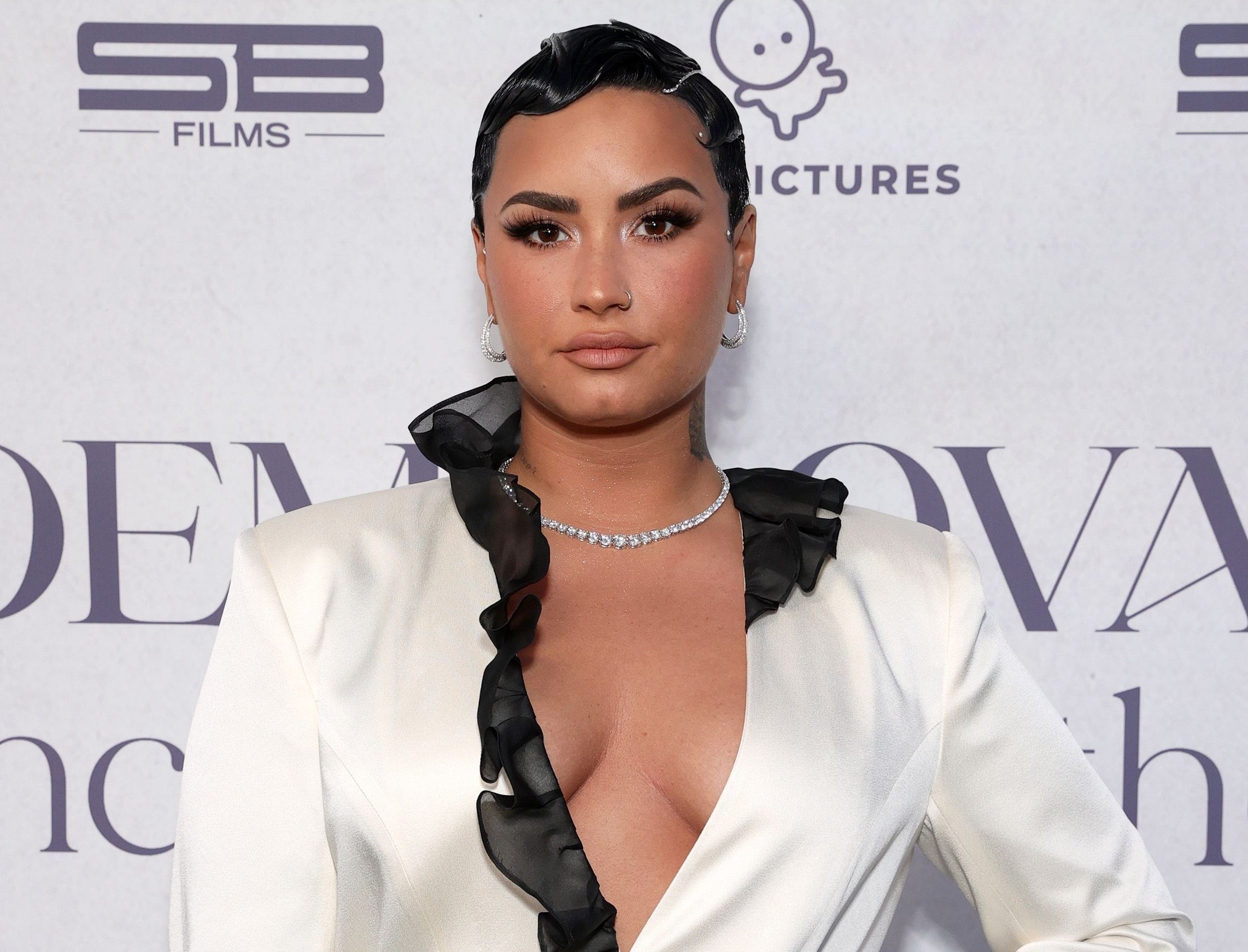 Demi wears a white blazer with black ruffle trim