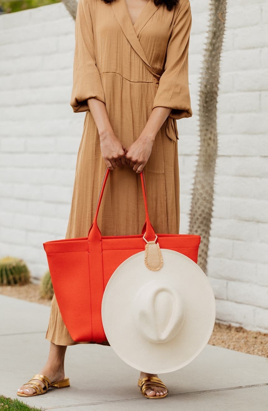 A hat hanging from the raffia clip attached to a tote handle
