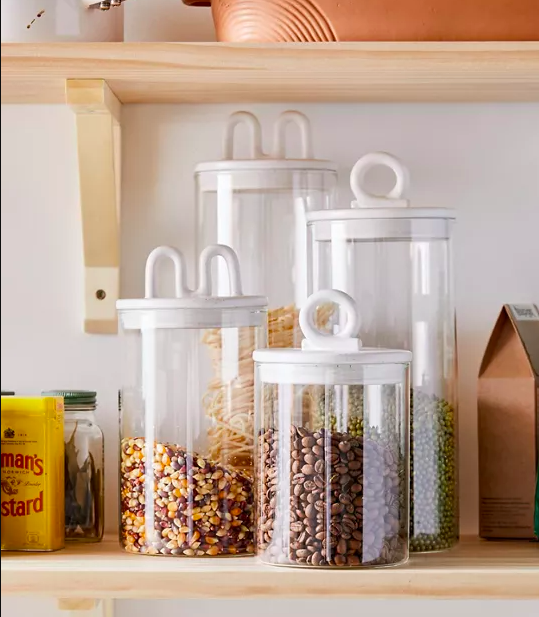 Four storage containers of different sizes filled with dried foods