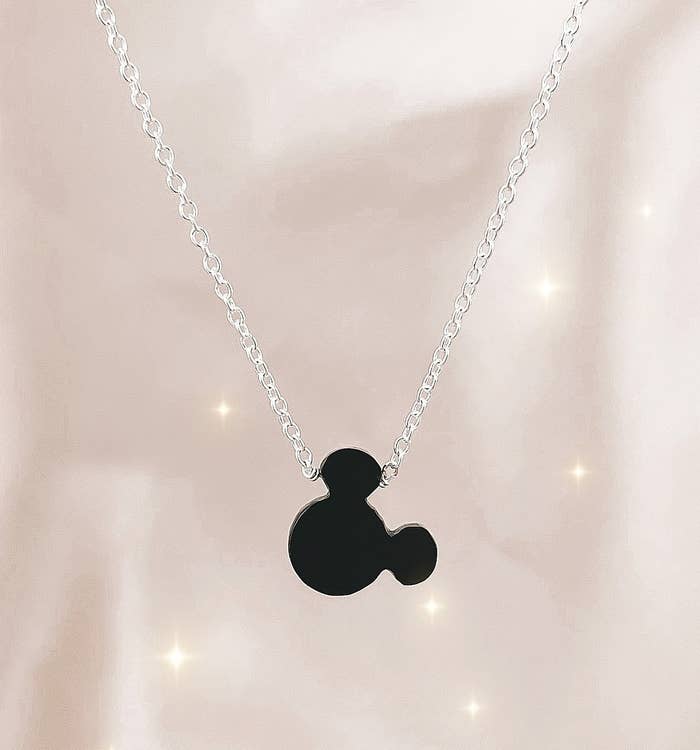 a silver chain with a black mickey charm on it