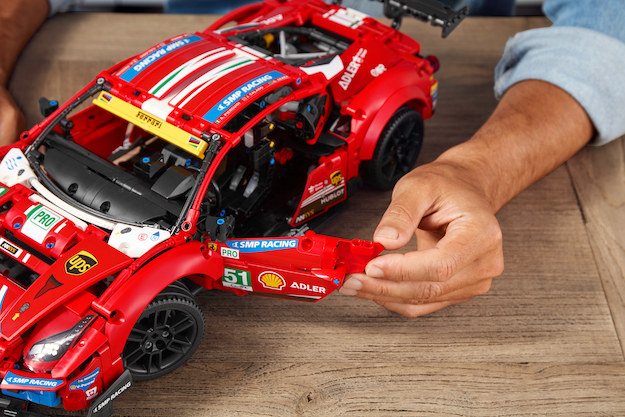 LEGO Ferrari set sitting on a table, with a hand opening one of the functional doors