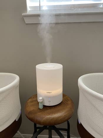 Abottle of vapor drops sitting next to a diffuser and a crib