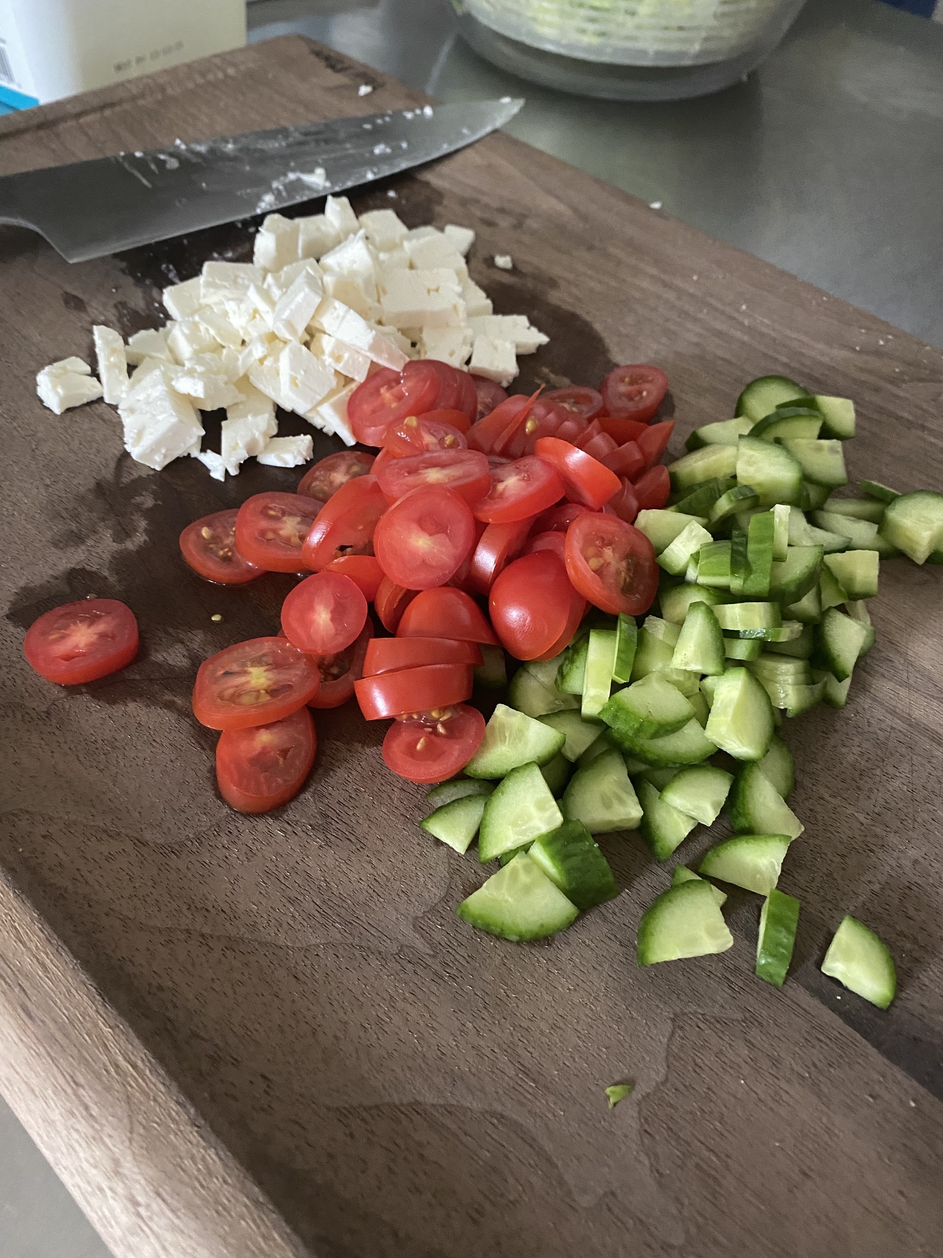 the writer&#x27;s cutting board holding cubed feta, cherry tomatoes, and cucumber