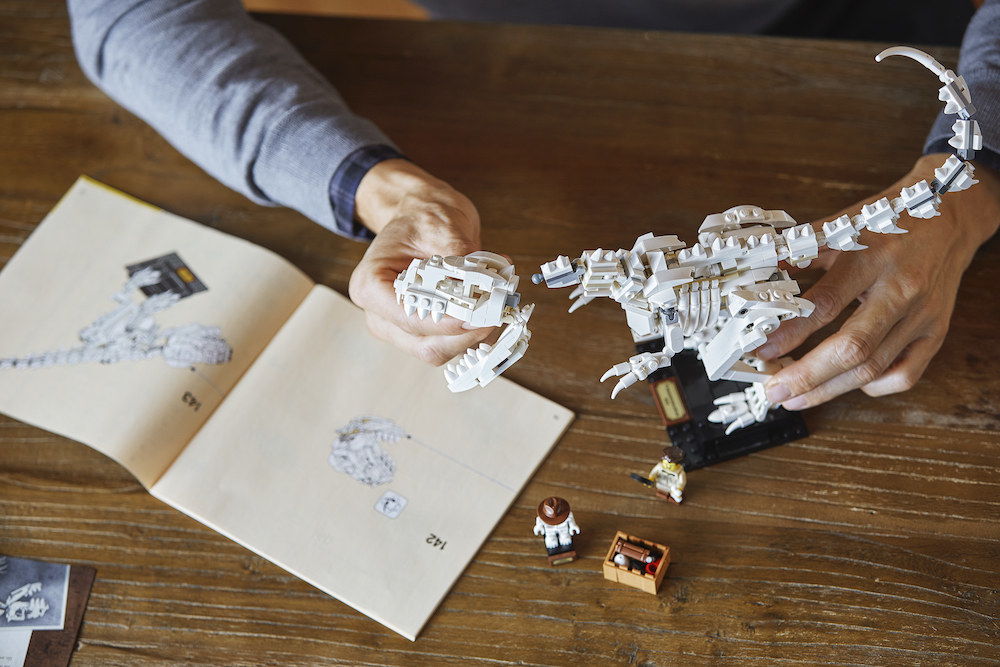 A LEGO T-rex being built on a wooden table