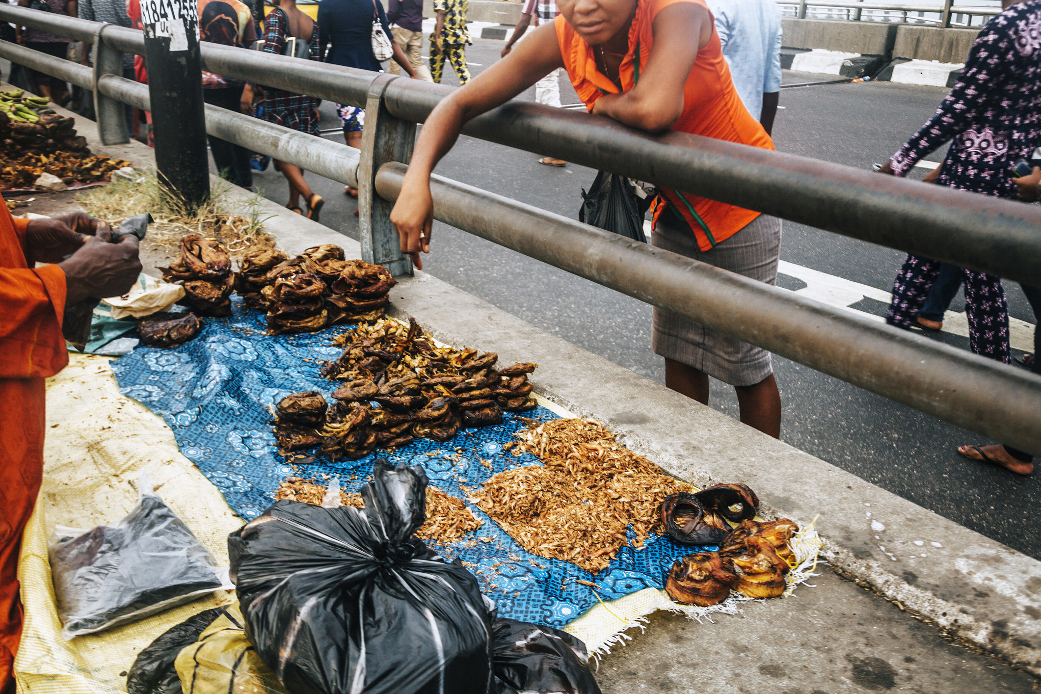 A boy selling food on the side of the road.