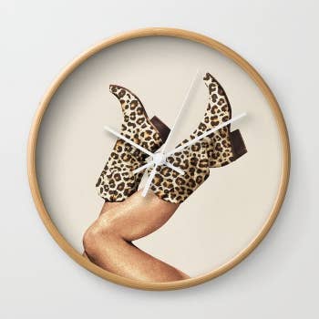 a beige wall clock with cowboy boots in leopard print