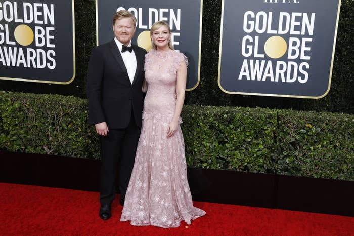Jesse, in a tuxedo, and Kirsten, in a sleeveless gown, pose for photos on the Golden Globes red carpet