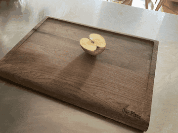 gif if the writer&#x27;s knife and cutting board being used to slice a red apple