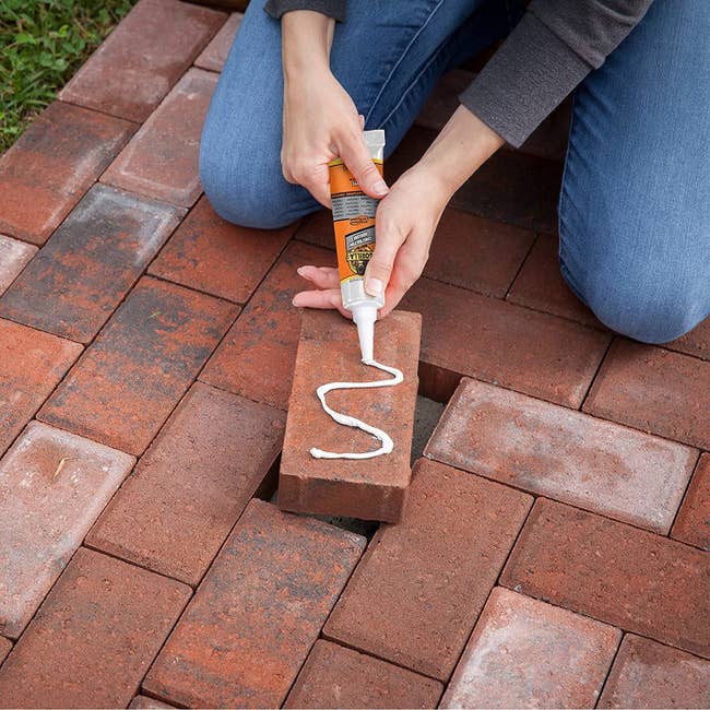 a model uses the gorilla glue to replace a brick in the pavement