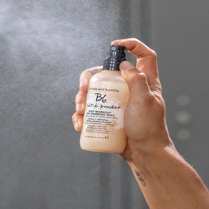 A hand spraying the dry shampoo mist