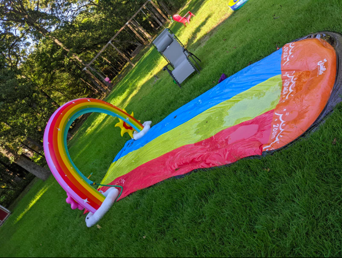 a reviewer&#x27;s photo of the blue, yellow, and red slip and slide on grass