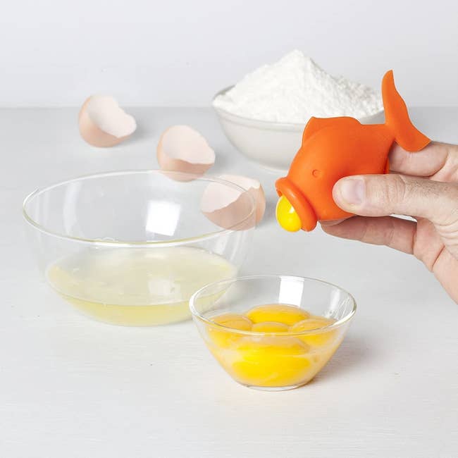 an orange fish-shaped tool sucking the yolk out of an egg