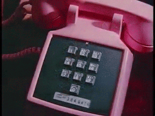A zoomed-in shot of someone dialing a pink landline phone