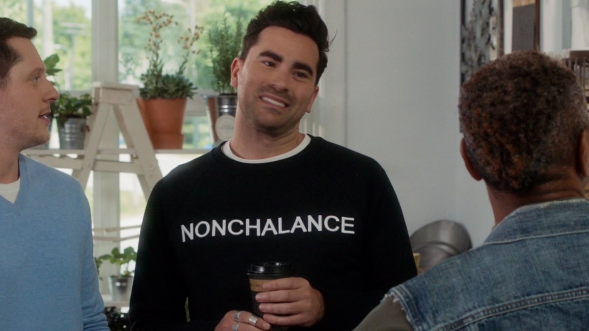 David Rose waring a black sweatshirt with &quot;Nonchalance&quot; written across the front in white letters.