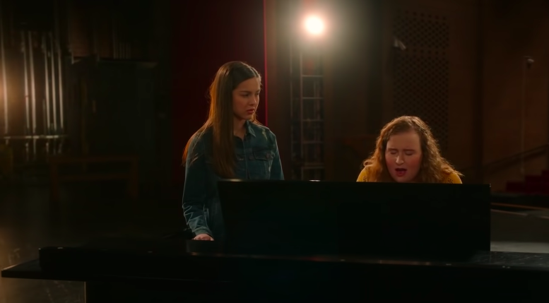 Nini and Ashlynn singing a duet behind a piano.