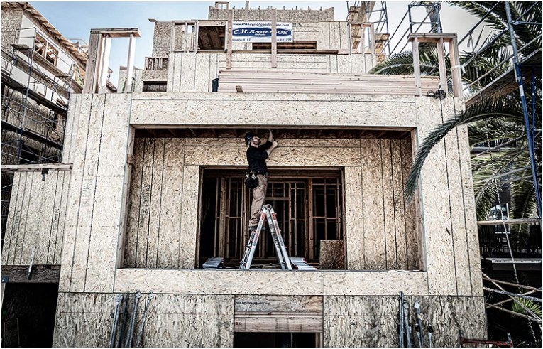 Foto de hombre utilizando escaleras para trabajar en costrucción de casa