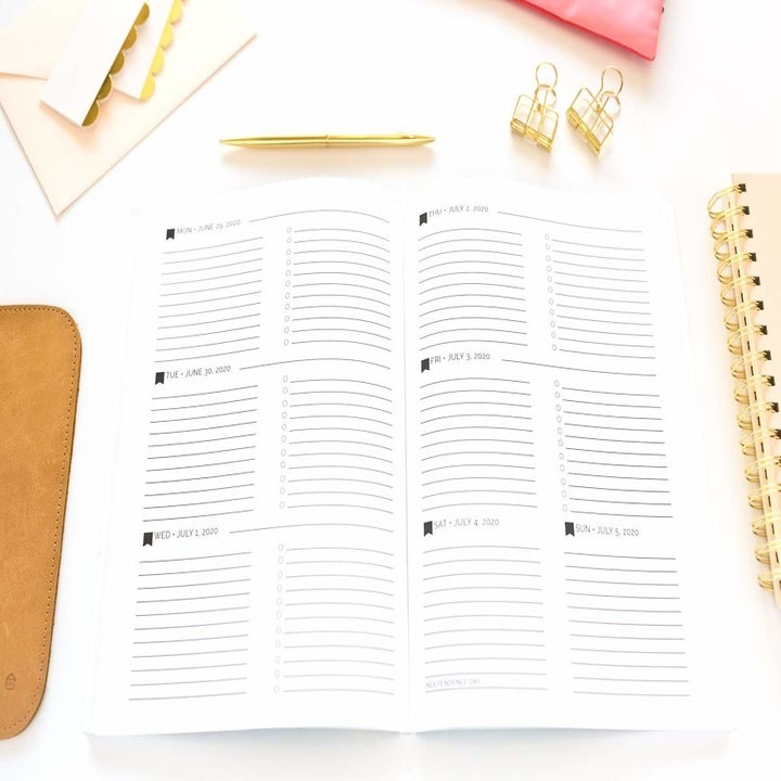 A small planner on a plain background with notebooks, binder clips, and an eraser nearby