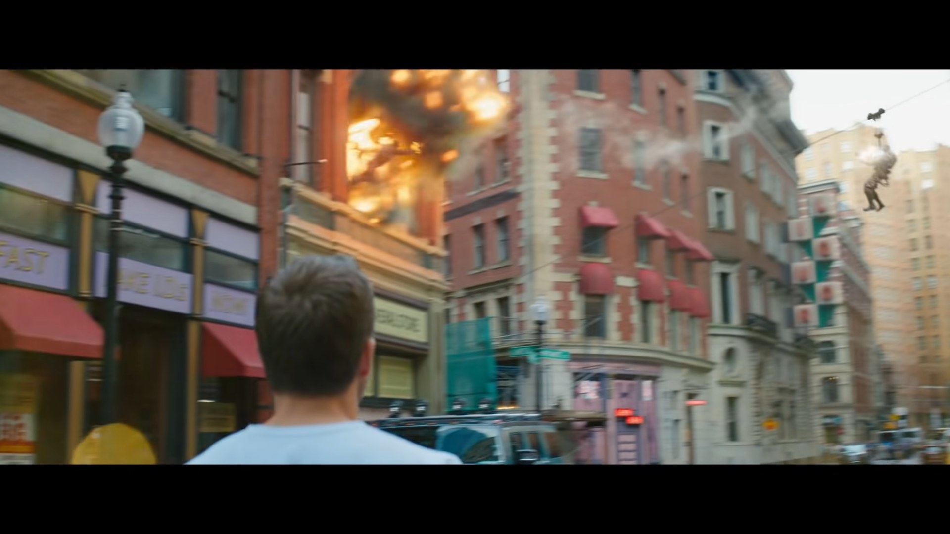 A man rappelling into a window and a man on fire falls out