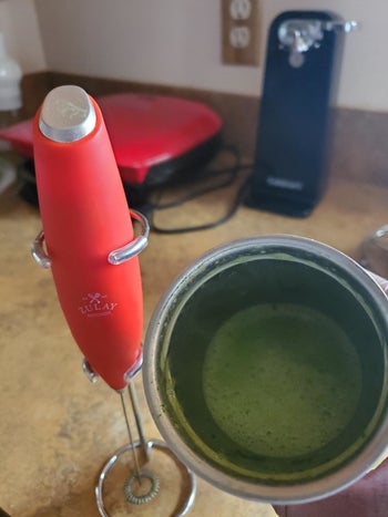 a reviewer's red frother next to a mug of matcha