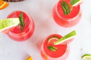 Three glasses of pink watermelon sangria, garnished with watermelon wedges on the rim