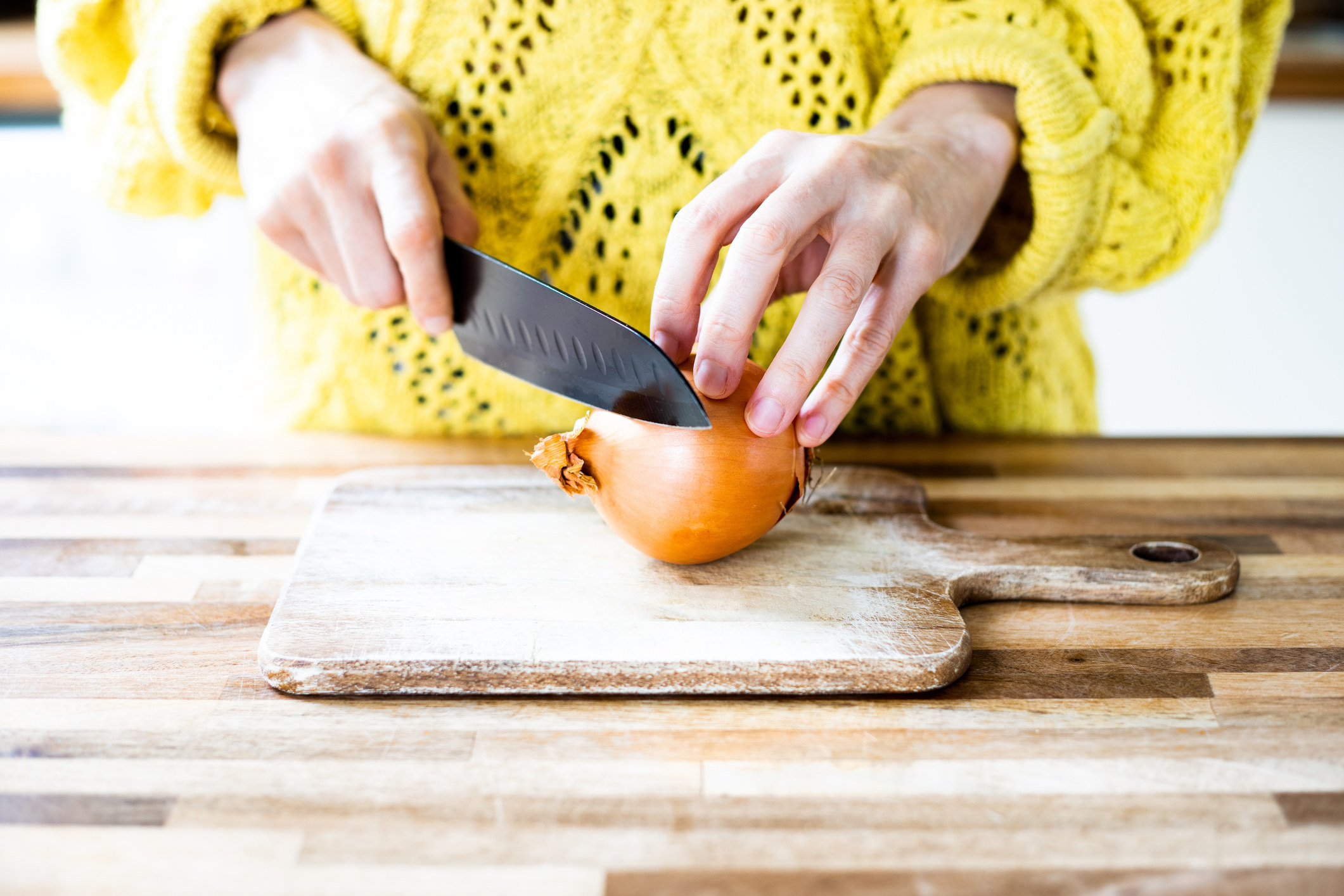 someone about to cut a sweet onion on a cutting board