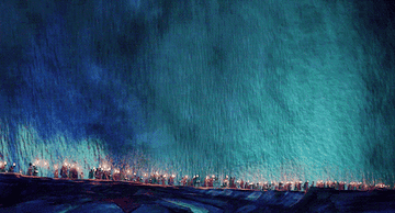 A large group of people march through a parted sea, while flashes of light reveal shadows of the large sea creatures encased in the water.