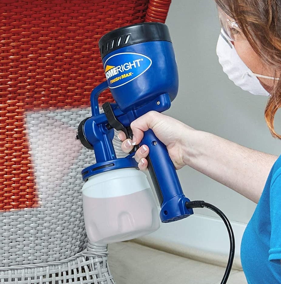 A person using the sprayer to paint a chair