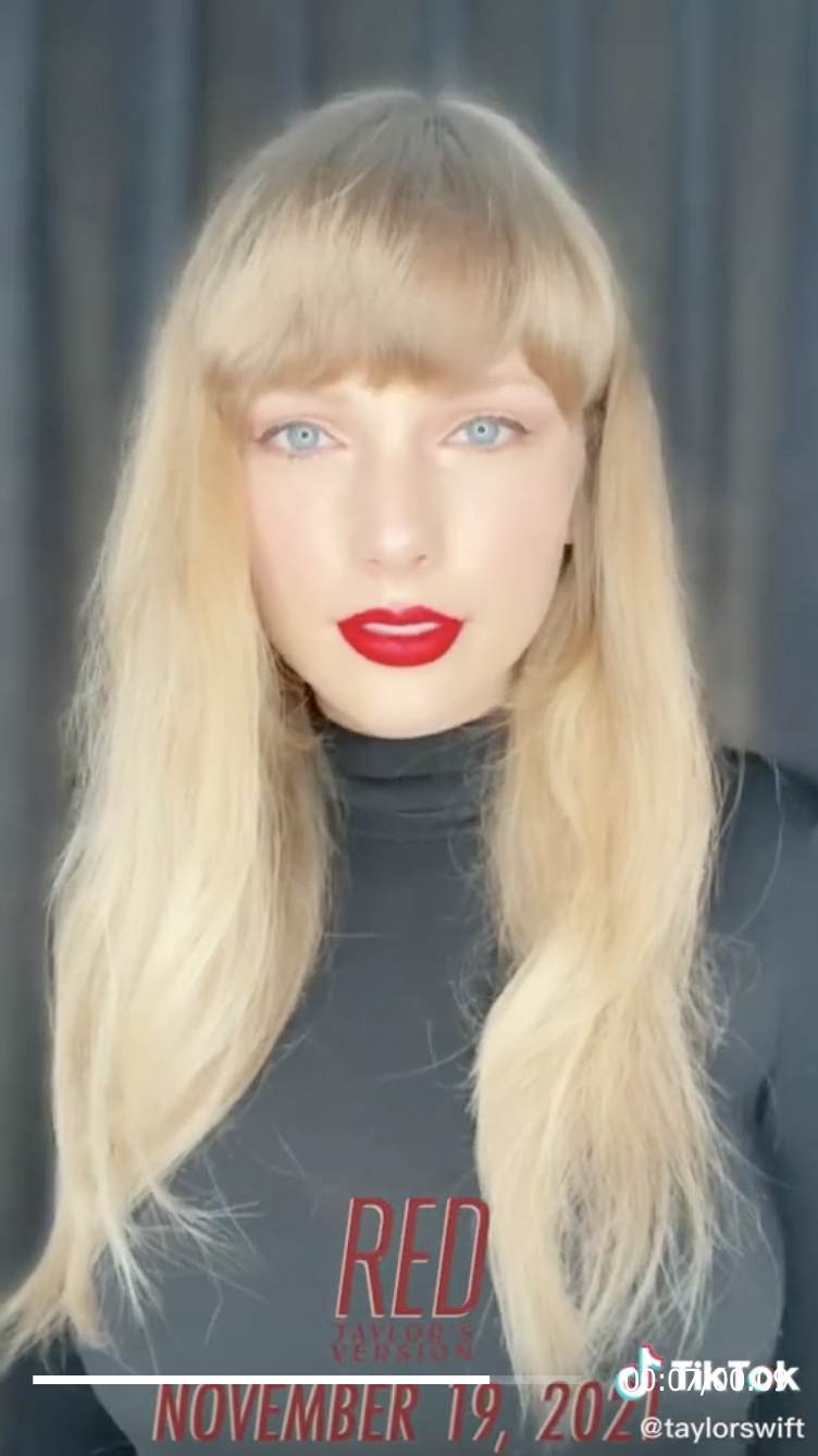 Taylor with long hair, bright red lipstick, and the caption "November 19, 2021"