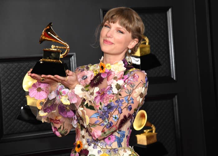 Taylor in a flowery outfit and holding up a Grammy