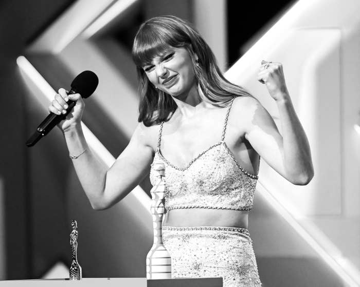 Black-and-white photo of Taylor with her fists raised in triumph and holding a microphone