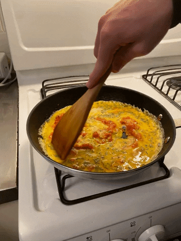 gif of a wooden spatula moving the egg mixture around the pan