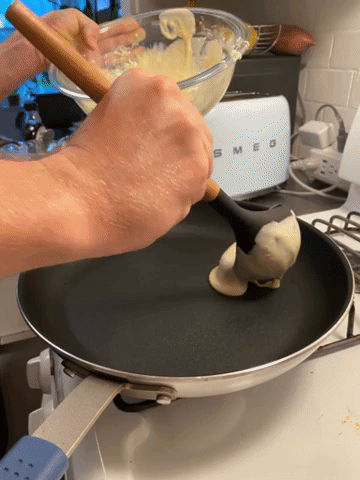 pancake batter being scooped with a laddle onto the pan