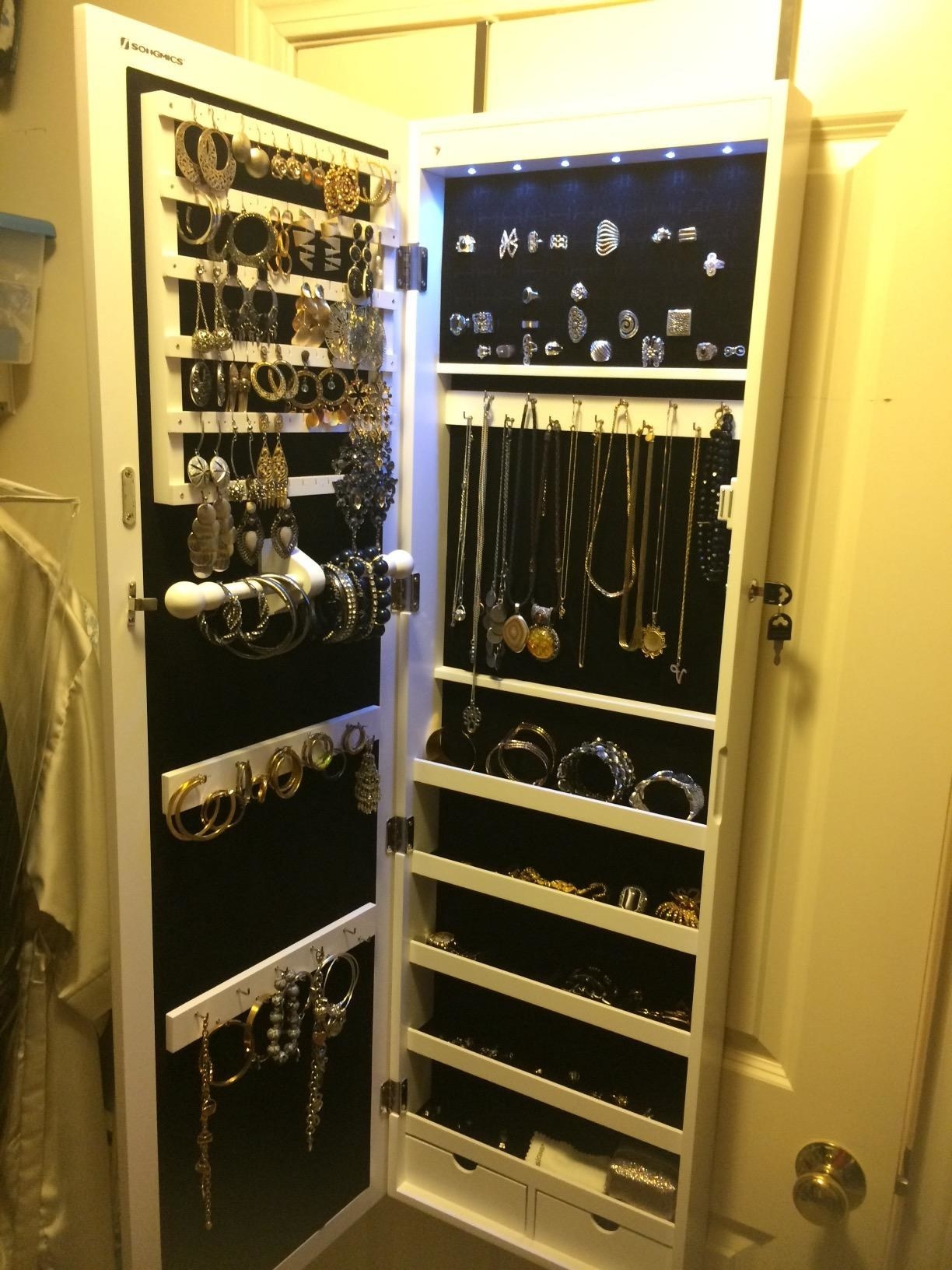 Reviewer&#x27;s jewelry cabinet open, with earring slots, hooks for necklaces and bracelets, plus shelves and drawers