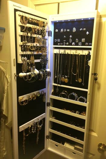 Reviewer's jewelry cabinet open, with earring slots, hooks for necklaces and bracelets, plus shelves and drawers