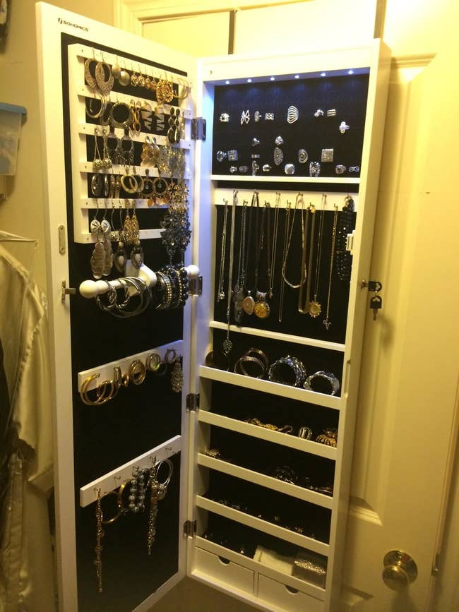 Reviewer's jewelry cabinet open, with earring slots, hooks for necklaces and bracelets, plus shelves and drawers