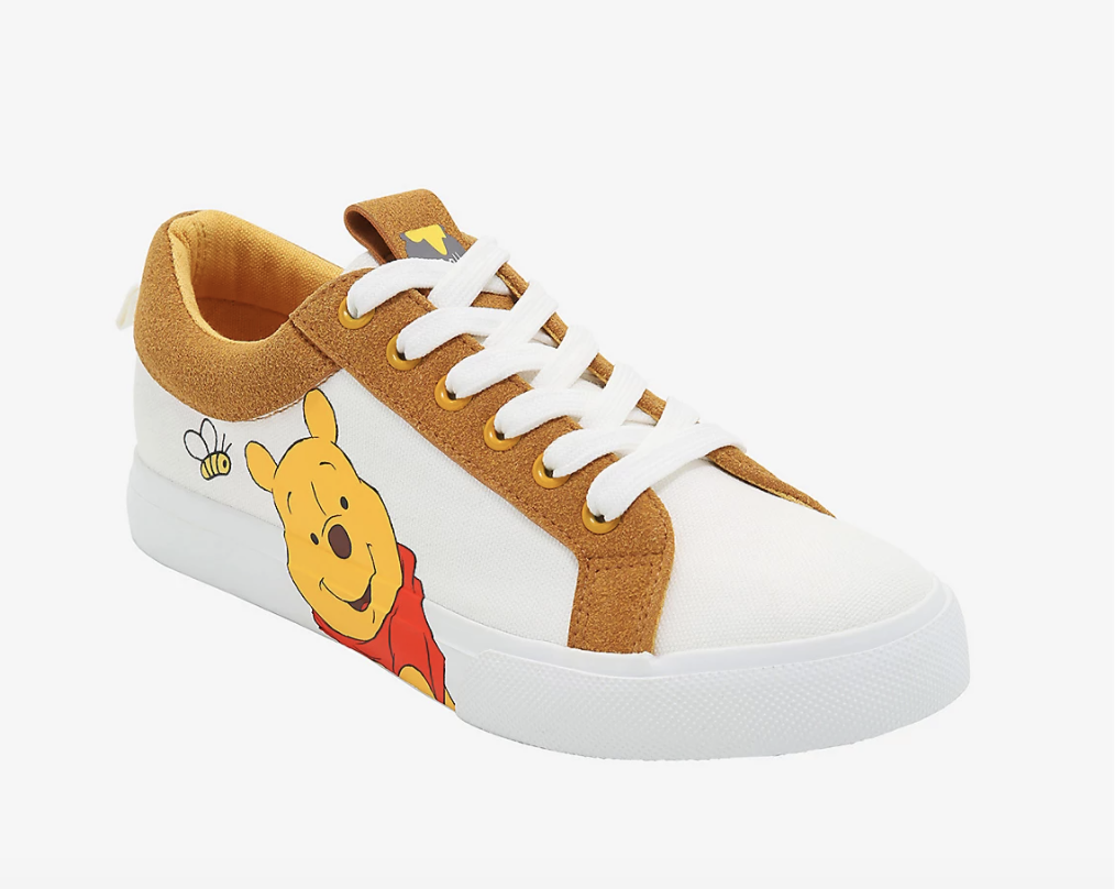 a white sneaker with tan suede accents and winnie the pooh on the side