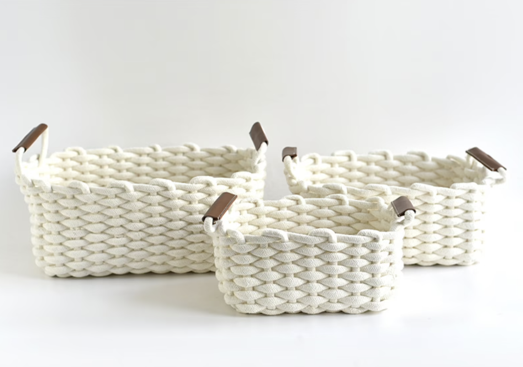 Three rectangular white cotton woven baskets with brown handles
