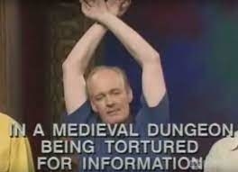 Colin pretending to be strung up by his wrists with text reading &quot;In a medieval dungeon being tortured for information&quot;