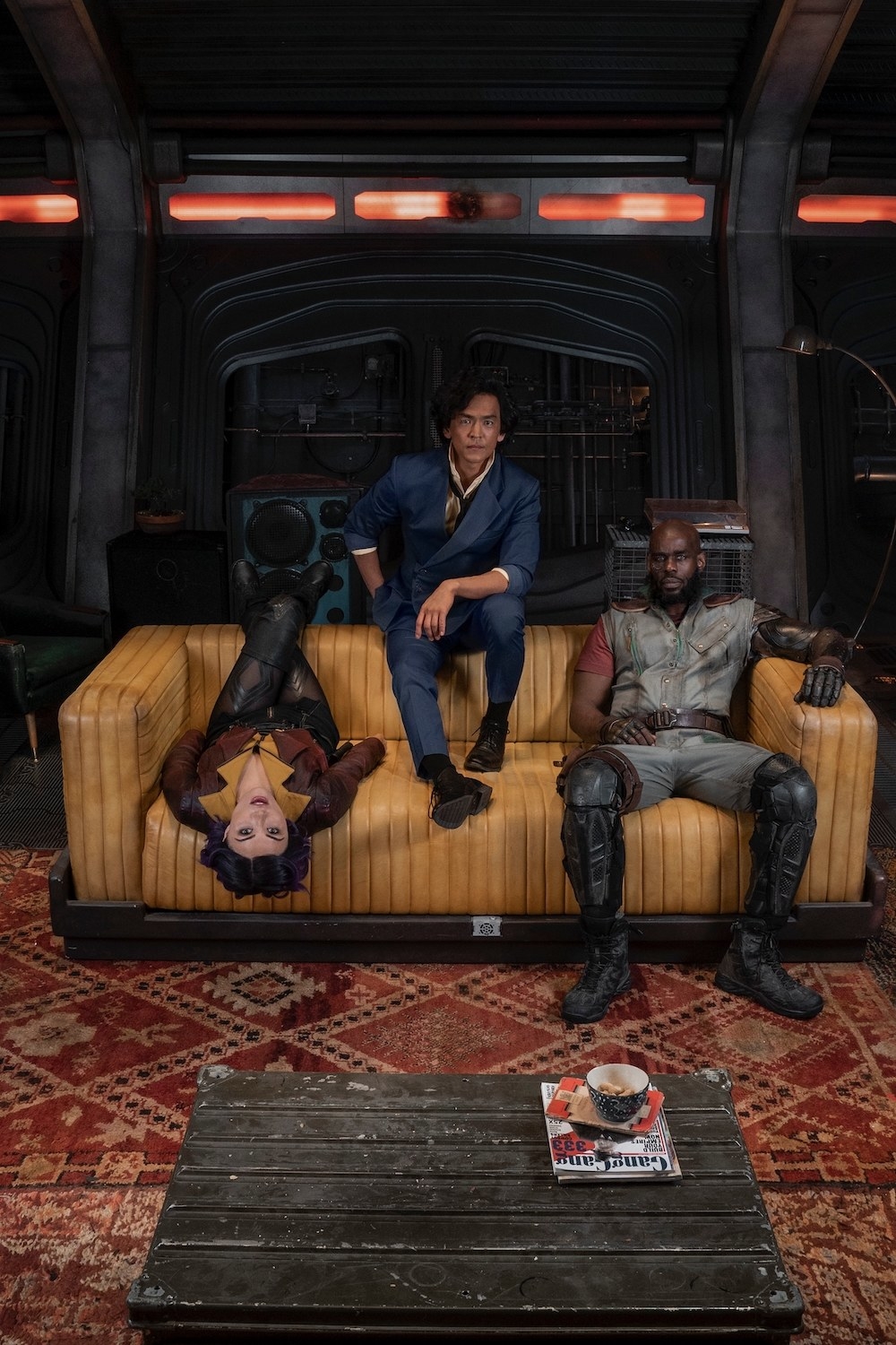 The cast in character lounging on a couch