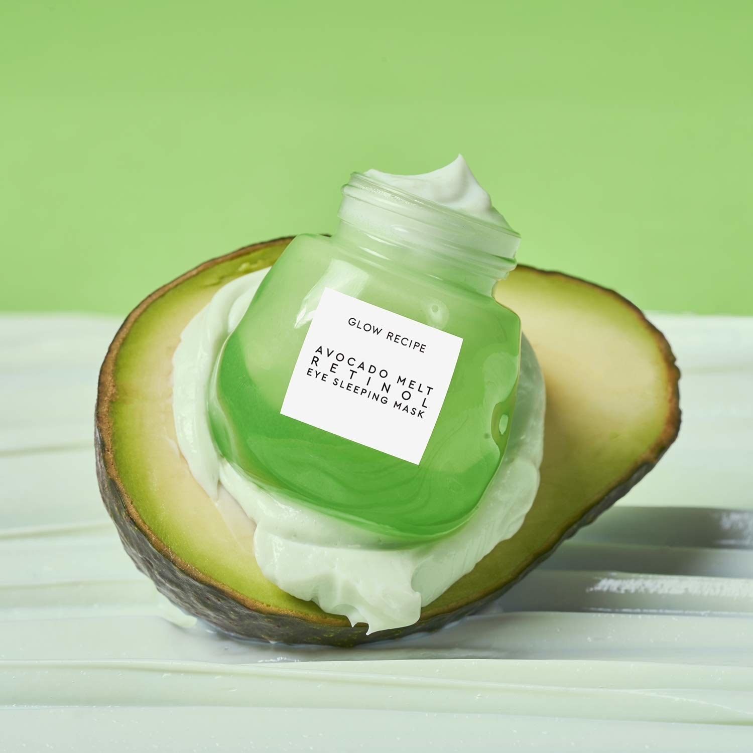 A small jar of the Glow Recipe Avocado Melt Retinol Eye Sleeping Mask is nestled into an actual avocado.