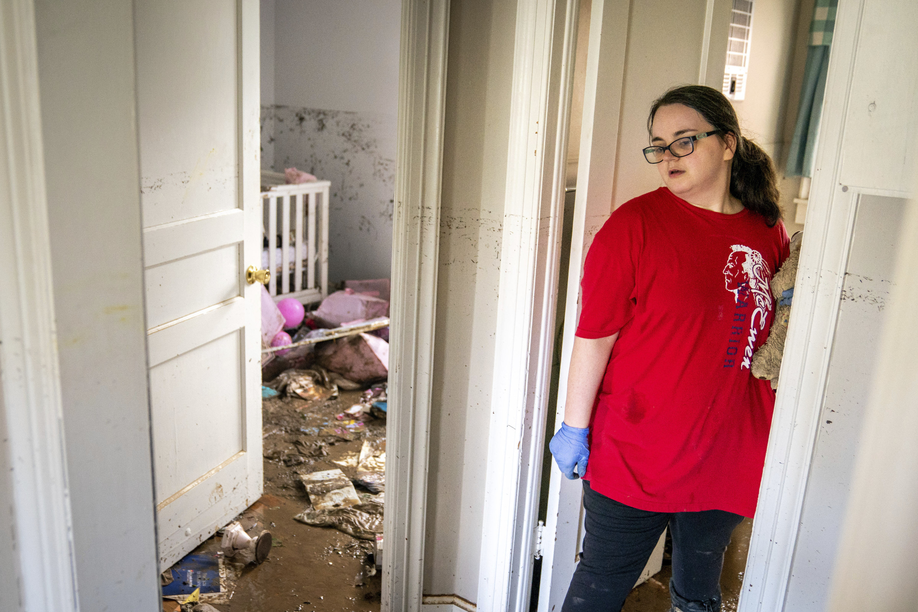 A woman stands by the doorway of a child's nursery with a muddy floor