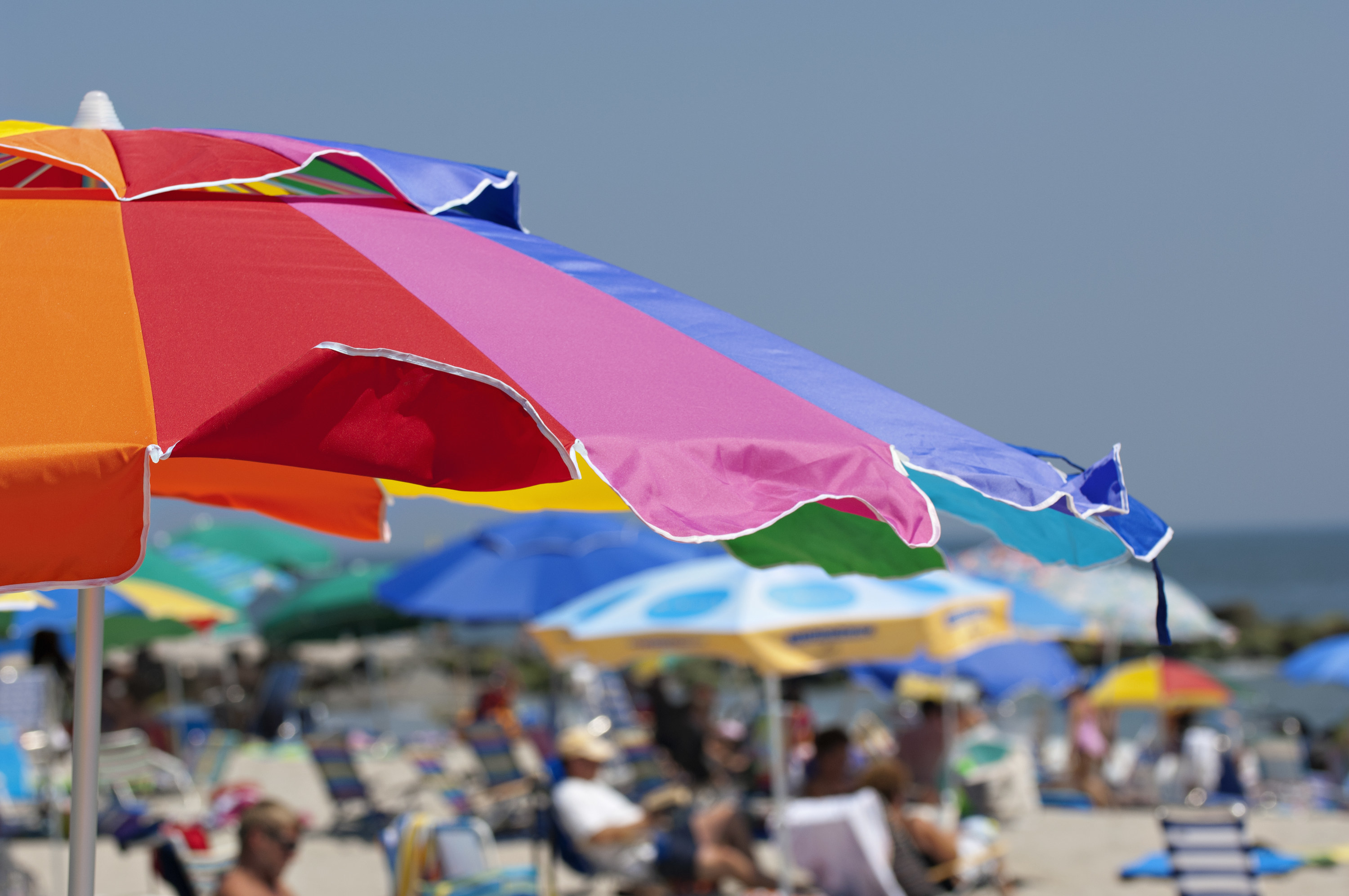 a beach umbrella with a blurry, busy beach in the background