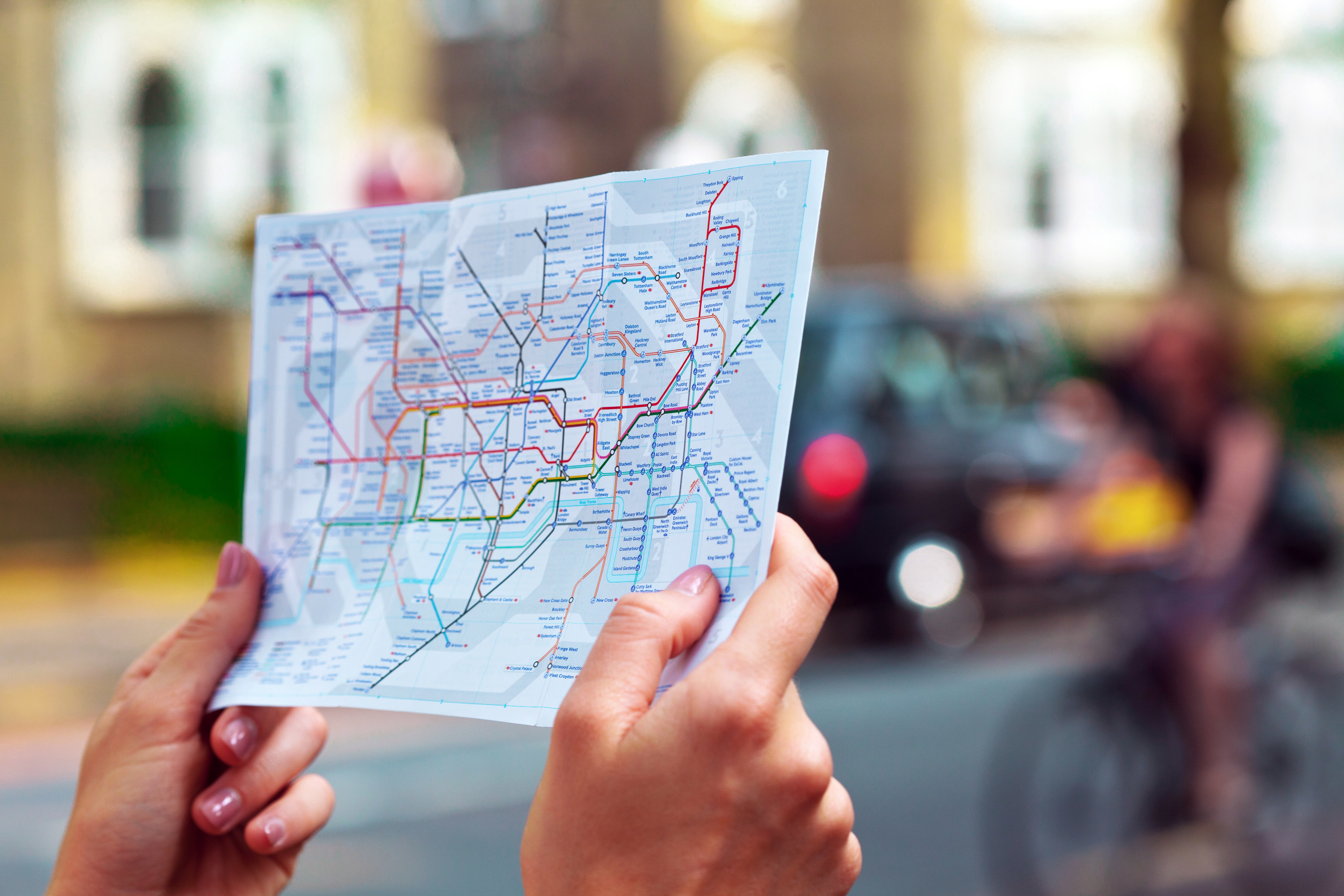 a person&#x27;s hands holding up the map for the London tube routes