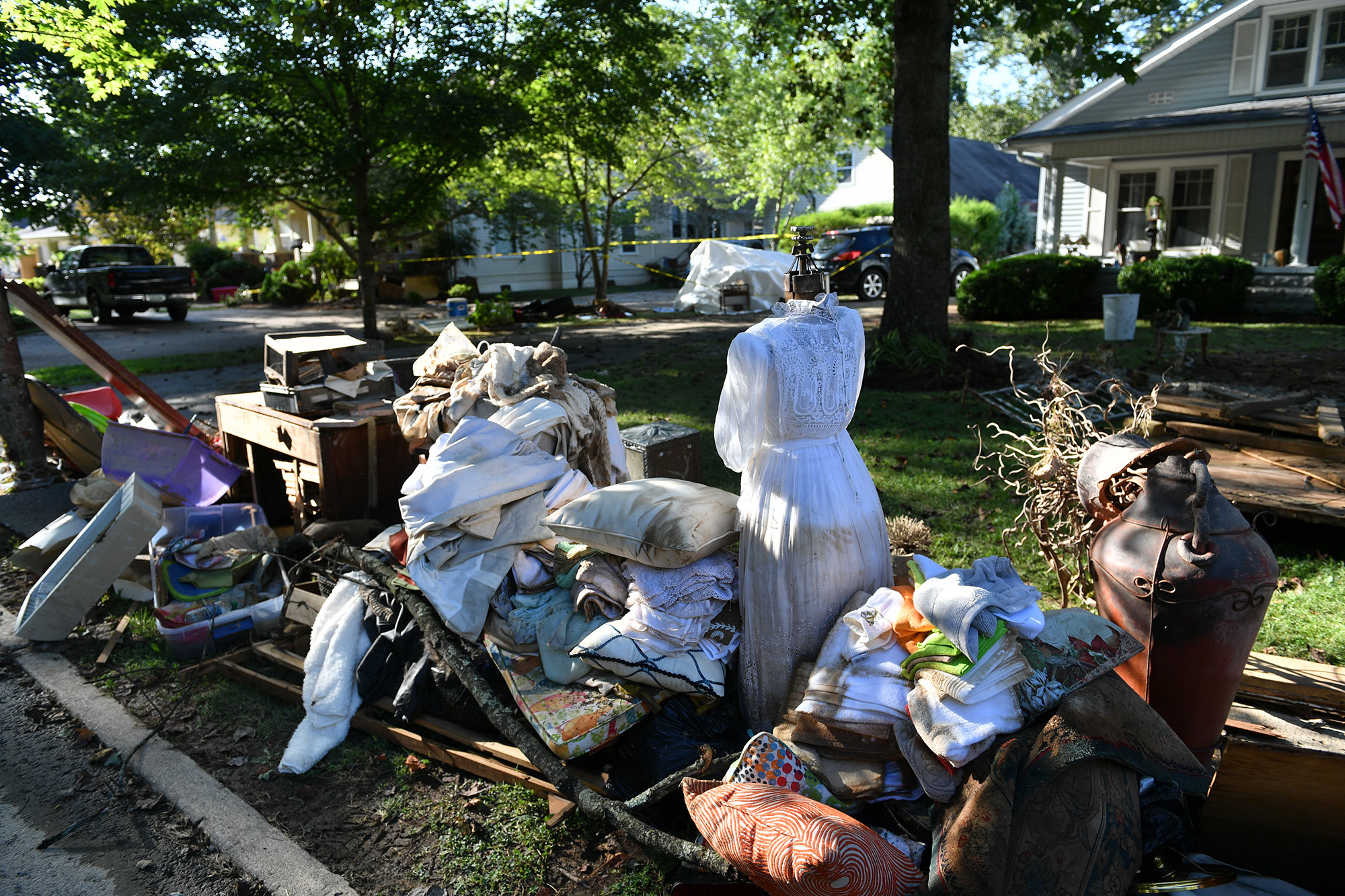 People&#x27;s belongings, including furniture, clothes, and pillows, sit near a sidewalk