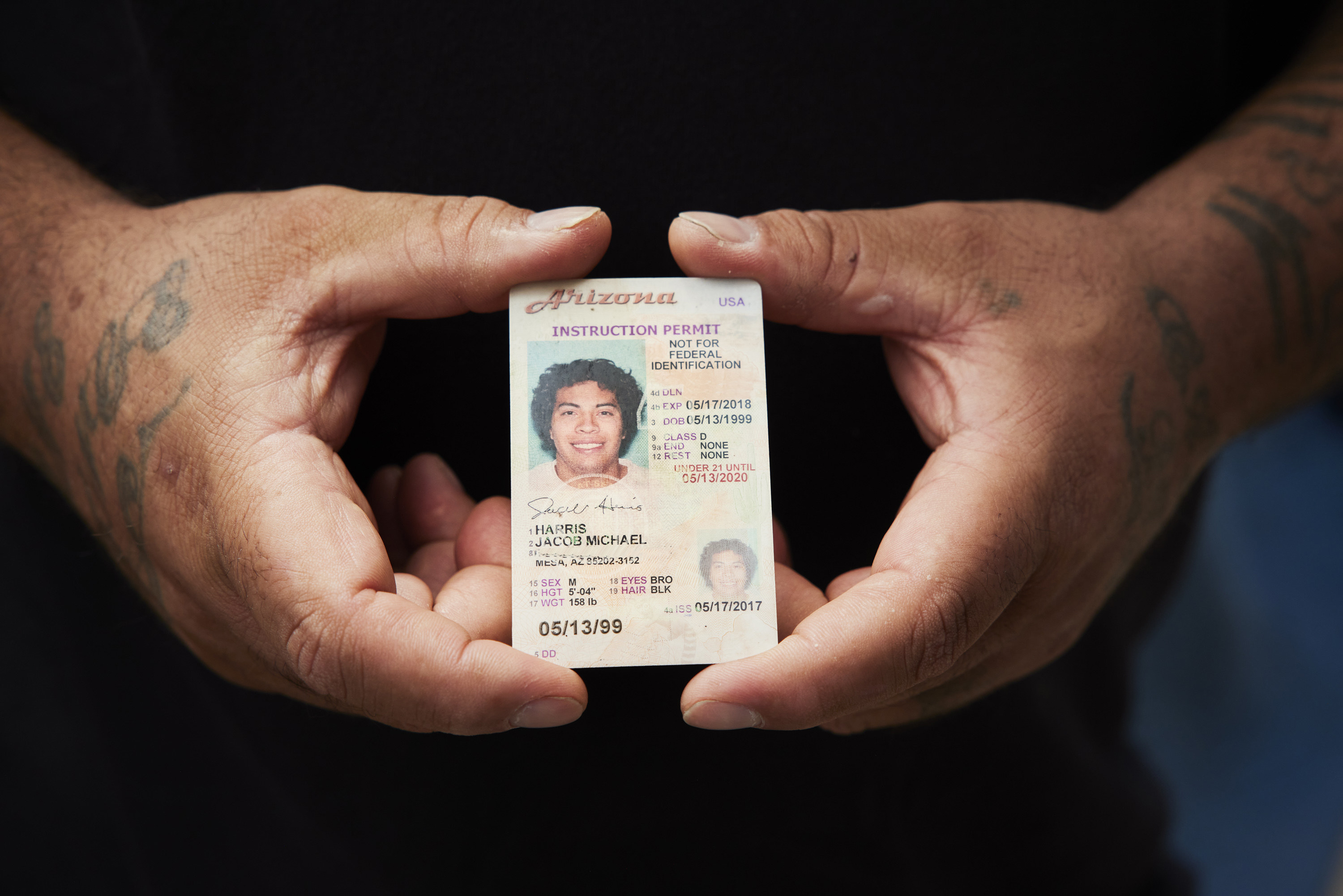 A man holds his son&#x27;s learners permit between two hands