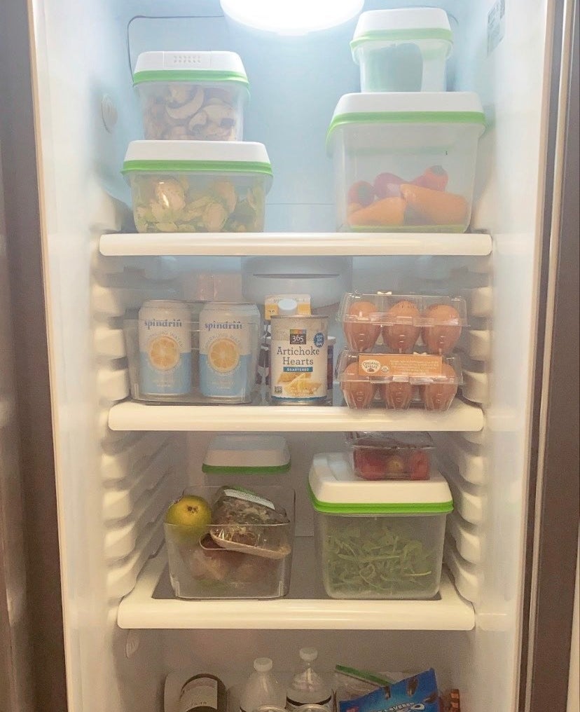 Inside of a fridge with various clear containers full of vegetables and fruit